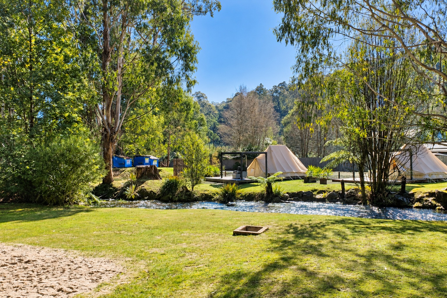 Riverside bell tents and timber decks among trees at Marysville Holiday Park.